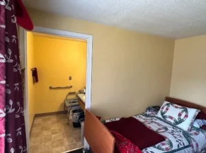 A room with a bed and a door open.